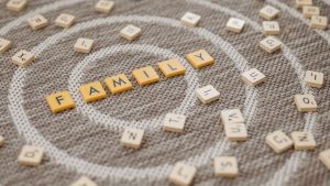 An artistic display of Scrabble tiles spelling 'FAMILY' on a textured carpet surface.
